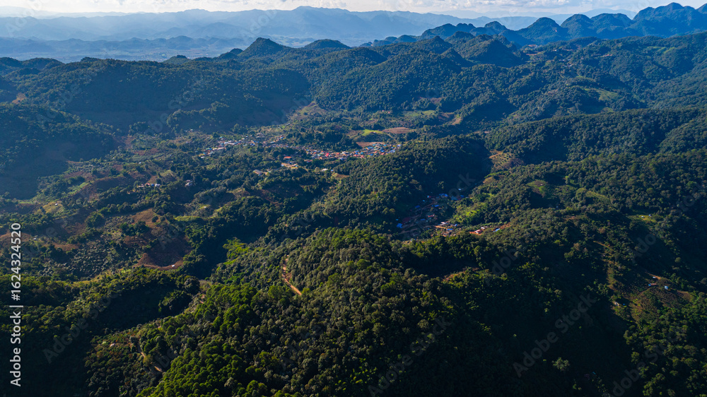 Obraz premium Scenic Road Through Tropical Mountain Landscape. aerial view of a winding road weaving through lush, tropical green hills under a clear blue sky. The road cuts gracefully across valleys and slopes