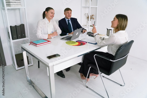 Business meeting in modern office with three professionals discussing strategies and ideas