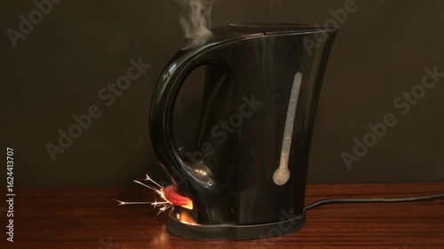 A burning electric kettle with smoke and fire on a wooden surface. Concept of household appliance malfunction and fire hazard.