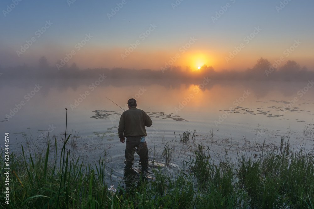 man fishing on the lake at foggy sunrise man fishing on the lake at foggy sunrise