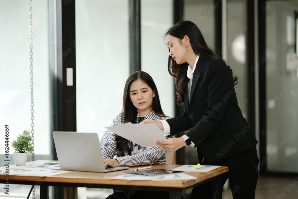 Fototapeta premium Two Asian businesswomen working together in an office.