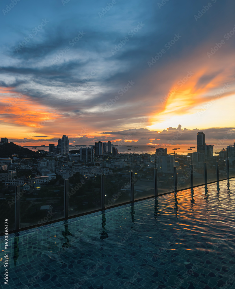 Fototapeta premium Stunning sunset over the city skyline from a rooftop pool in urban high-rise
