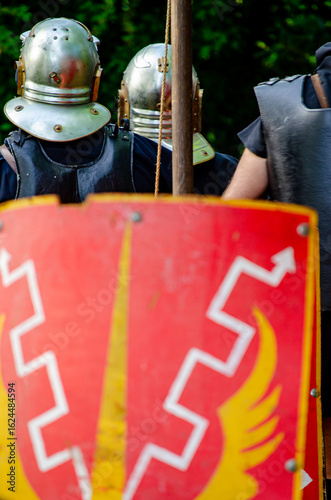 Canvastavla A Roman helmet with cheek guards on a painted shield, authentic historical prop