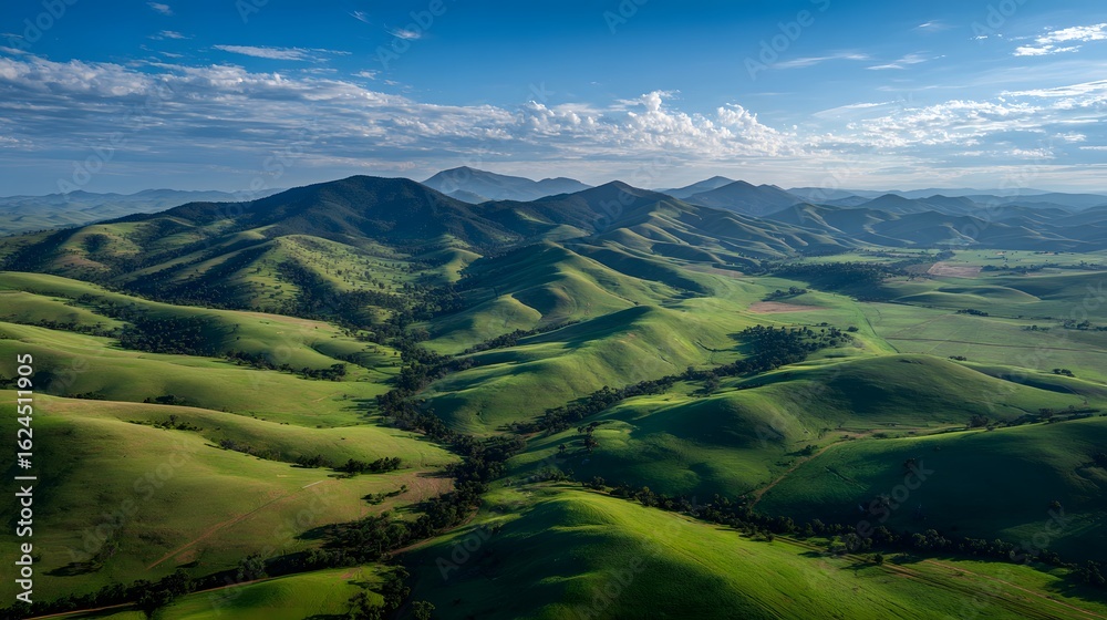Obraz premium Rolling green hills covered soft grass under a clear sky with midday sunlight birds eye view capturing expansive open fields and farmlands pure natural lighting no artificial effects
