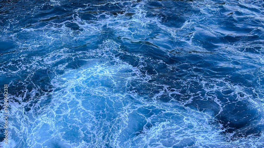 Obraz premium Blue sea water texture with frothy waves. White foam texture background with turquoise and blue colors, perfect for natural backgrounds and ocean themed designs.