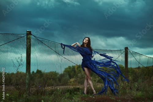 Dramatic Fashion Portrait Set in Nature Featuring Blue Flowing Fabric Amidst the Scenery