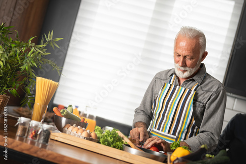 Happy senior man cooks with pleasure