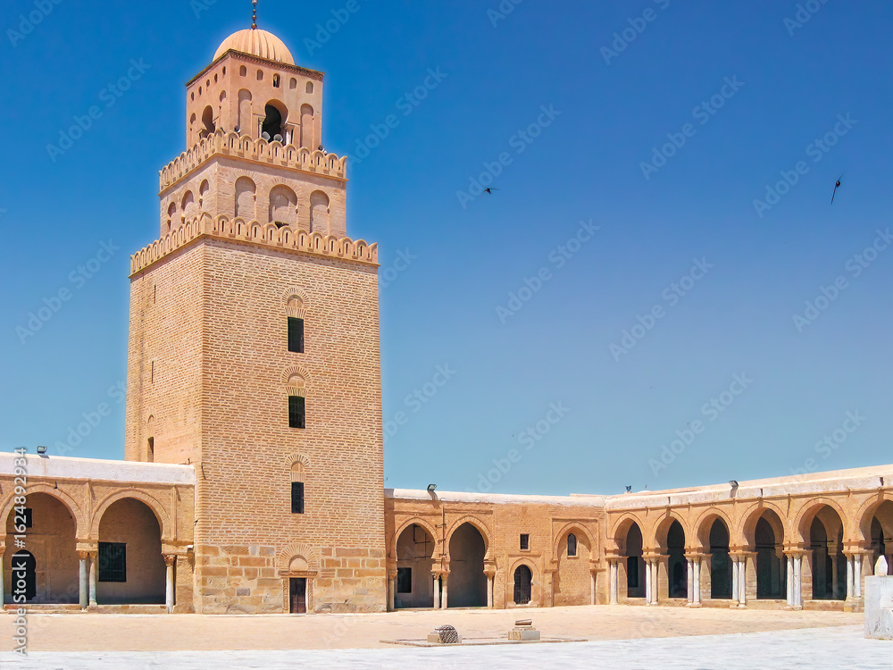 Fototapeta premium The minaret of the Great Mosque of Kairouan rises from sunlit silence — a fortress of faith built in stone, centuries before the first cathedral bell.