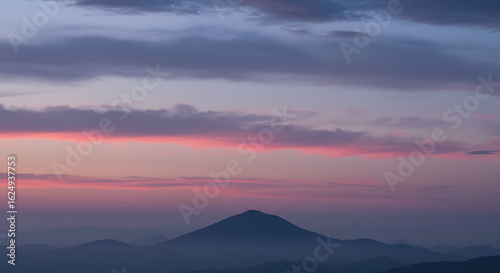 Majestic mountain silhouette against a vibrant sunset sky with pink and purple hues creating a
