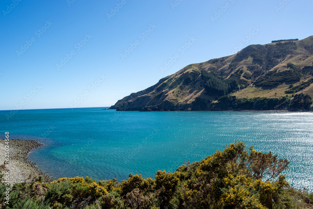 Fototapeta premium Serene Coastal Landscape with Blue Ocean and Green Hills