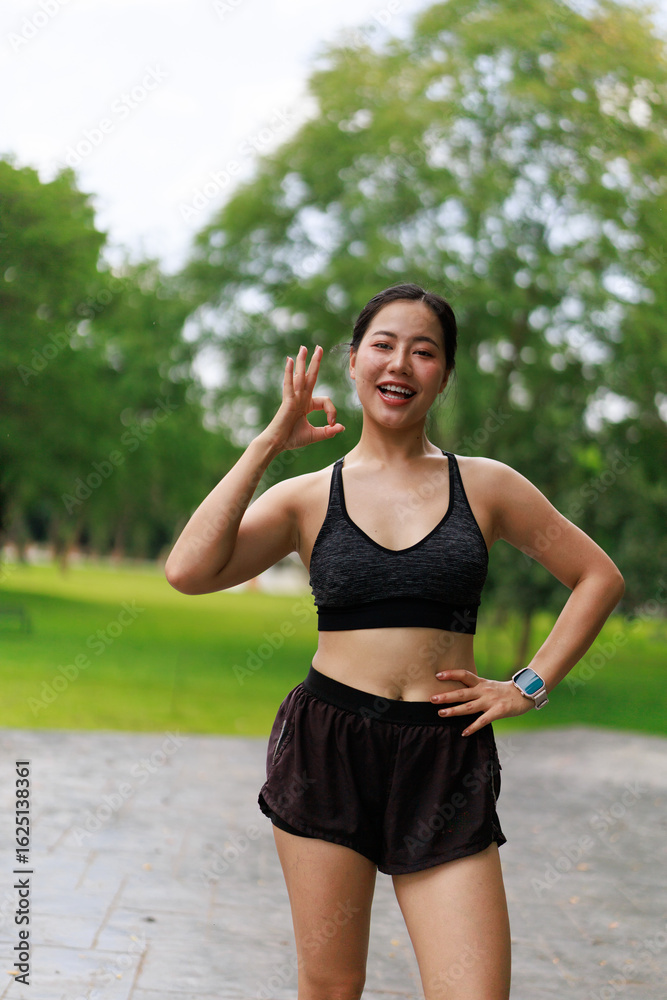 Fototapeta premium Young sportswoman gesturing ok sign after training in the park