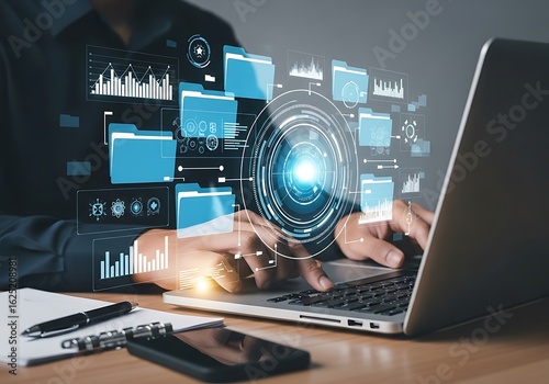 Photo of closeup of a persons hands on a laptop, interacting with a futuristic holographic interface displaying data charts, files, and a central glowing hub