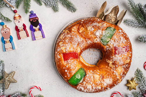 Foto Roscon de reyes with cream and christmas ornaments on a white background, top view