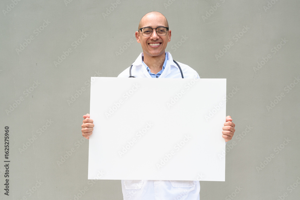 Hispanic Male Doctor in Lab Coat with Stethoscope on Plain Background Holding Empty Placard Hispanic Male Doctor in Lab Coat with Stethoscope on Plain Background Holding Empty Placard