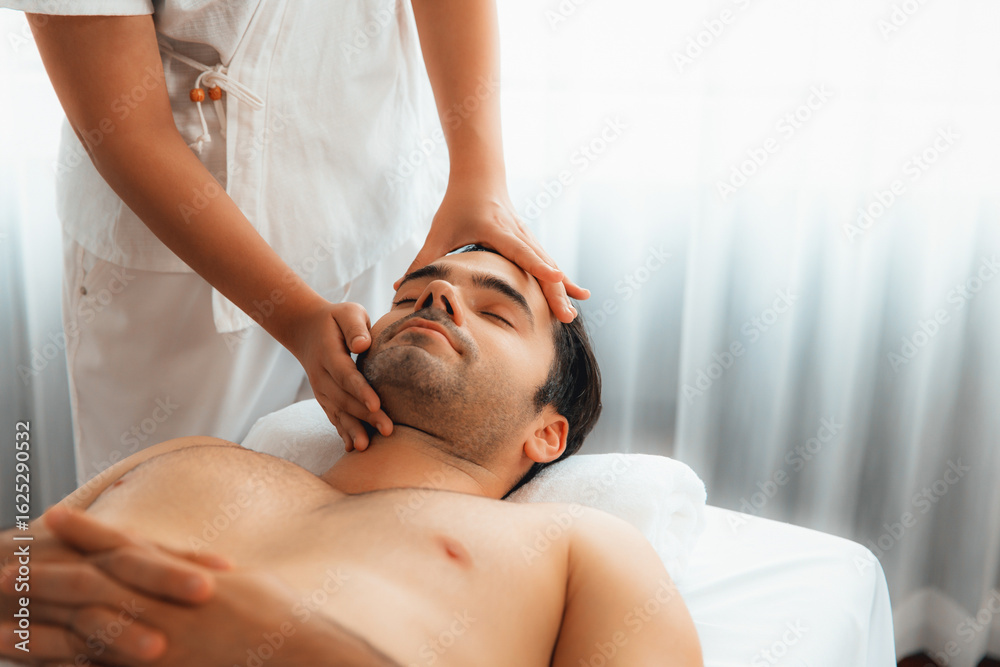 Obraz premium Caucasian man enjoying relaxing anti-stress head massage and pampering facial beauty skin recreation leisure in dayspa modern light ambient at luxury resort or hotel spa salon. Quiescent