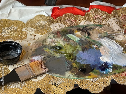 Close-up of artist palette with paint and brush – art supplies background