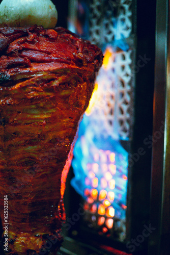 Mexican food. A meat trompo for tacos al pastor with dramatic night lighting and retro or vintage inspiration.