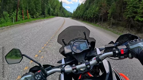 Adventure motorcycle  leaning while riding around twisty highway corners dense forest