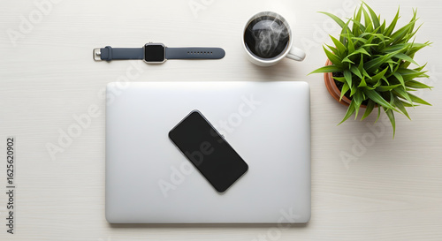 Minimalist Work Desk Flatlay with Closed Laptop, Phone, Smartwatch, Coffee Mug, and Potted Plant