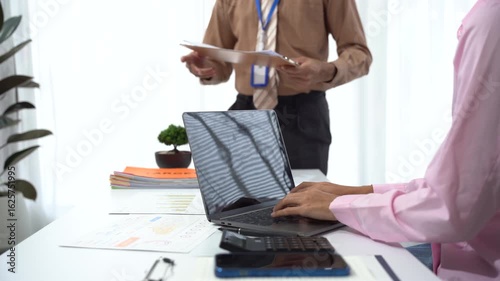Office Consultation: Collaboration and communication in a modern office setting, highlighting a focused laptop user engaging in consultation with colleague. 