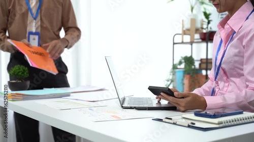 Office Collaboration Scene: Two colleagues in professional attire engaged in collaborative work within a contemporary office environment.
