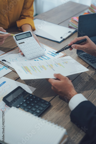 Two business people talk project strategy at office meeting room. Businessman discuss project planning with colleague at modern workplace while having conversation and advice on financial data report.