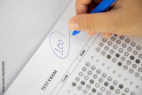 shows a hand holding a blue pen and writing the number 