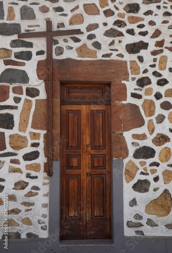 Puerta de madera antigua con cruz en muro de piedra