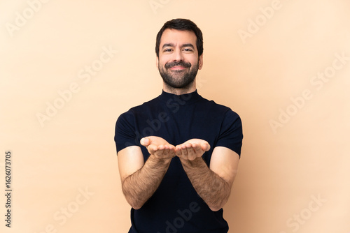 Caucasian handsome man over isolated background holding copyspace imaginary on the palm to insert an ad