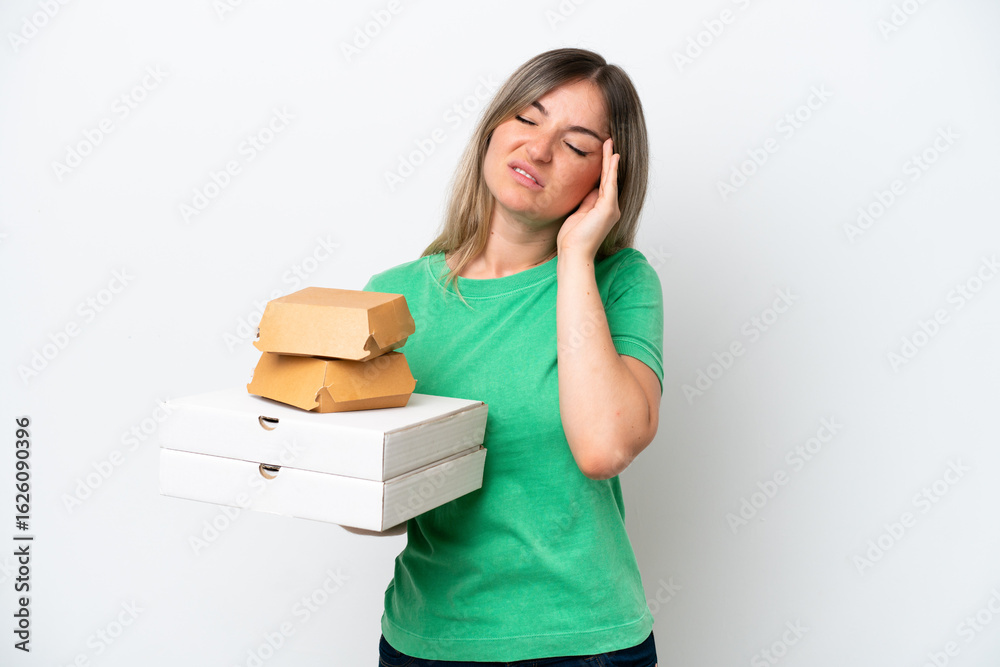 Young Rumanian woman holding fast-food isolated on white background with headache Young Rumanian woman holding fast-food isolated on white background with headache