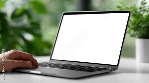Technology presentation mockup featuring close-up of modern laptop with white display screen on white table, man’s hand visible for interaction in sleek minimal interior background

