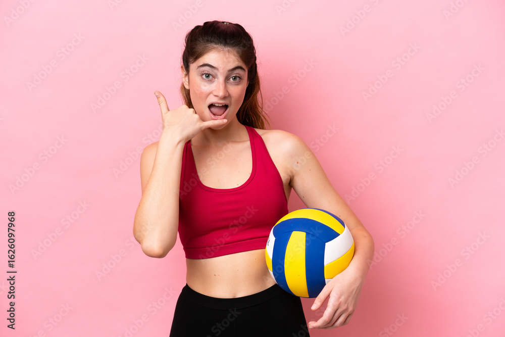 Young caucasian woman playing volleyball isolated on pink background making phone gesture. Call me back sign Young caucasian woman playing volleyball isolated on pink background making phone gesture. Call me back sign