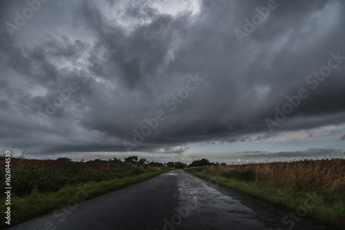 Vászonkép WEATHER - Dramatic black rain clouds over fields and country road