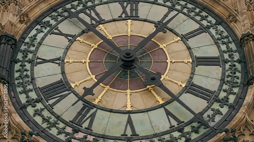 Detail view of an ornate clock face with roman numerals and filigree details, on a tower
