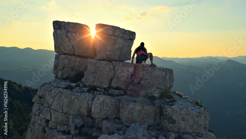 Foto Environmental portrait of a runner atop a rugged cliff at sunrise, silhouetted against the golden horizon