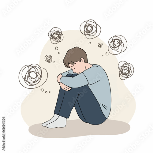 Sad young man sitting alone with knees to chest and thinking  
