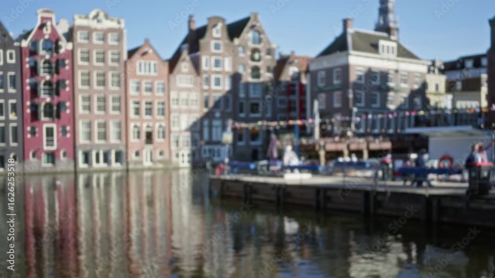 Defocused view of amsterdam's iconic canals lined with historic dutch architecture reflecting in the water under clear skies, capturing a blend of urban details and vibrant colors. Defocused view of amsterdam's iconic canals lined with historic dutch architecture reflecting in the water under clear skies, capturing a blend of urban details and vibrant colors.