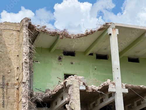 partially demolished concrete building with exposed rebar and crumbling edges