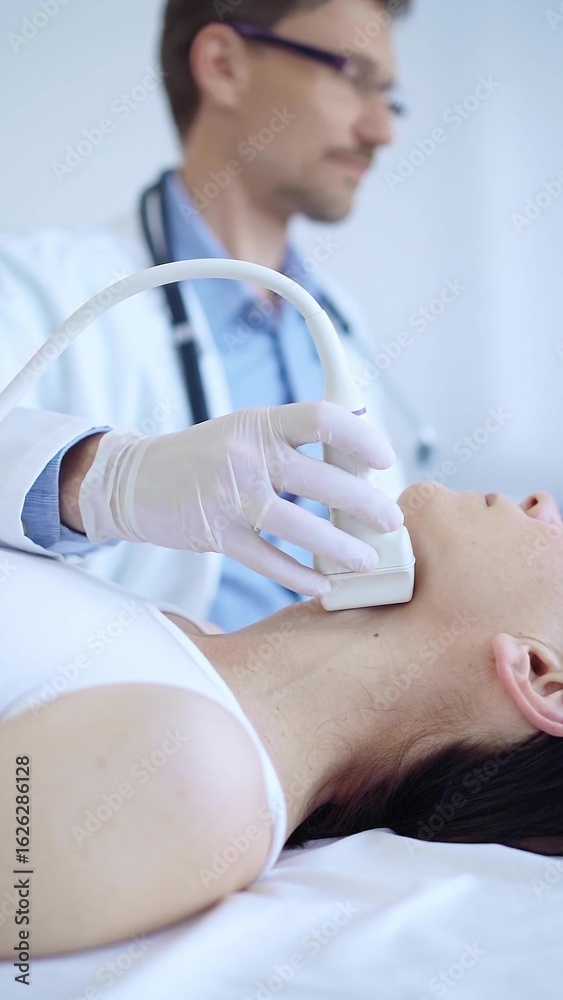 Obraz premium Doctor man wearing white protective gloves is using ultrasound machine to examine neck of female patient in hospital. Medicine, thyroid gland health