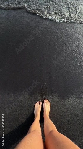 legs on the black sand with ocean water