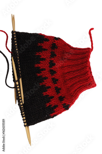 Knitted woolen sleeve cuff with knitting needles, isolated on a white background.
