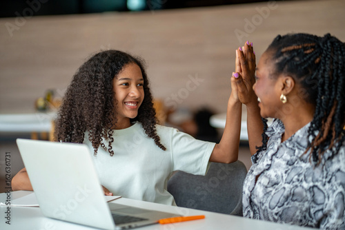 African school teacher is teaching and guiding young student and having high five in the class using information from experience and internet for academic literacy study and education usage