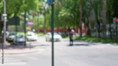 Wallpaper Mural Blurred urban street with cars driving and person crossing at intersection in daytime with green trees Torontodigital.ca