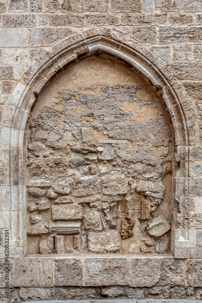 Fototapeta premium Ventana de forma ojival cerrada con piedras y restos arqueológicos de una iglesia.