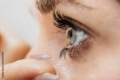 Fotografie Close-up of a woman applying a contact lens to her eye, showcasing the delicate