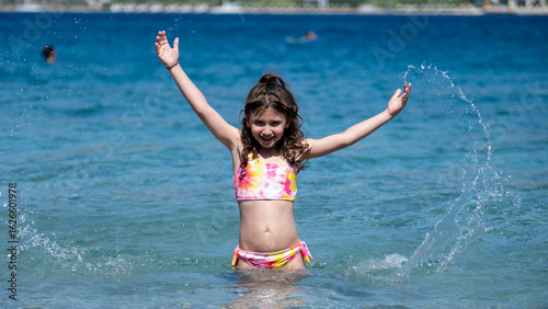 A sweet little girl child joyfully playing in the sea during vacation, enjoying the summer