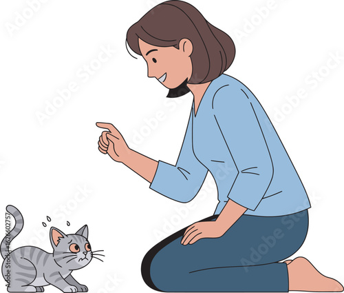 A smiling woman with brown hair kneels while interacting with a small nervous grey tabby kitten.