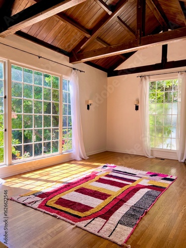 Sunlit Interior with Vaulted Wood Ceiling and Modern Geometric Rugsunlit room, vaulted ceiling, exposed beams, hardwood floors, modern rug, geometric rug, interior design, natural light, boho decor, C