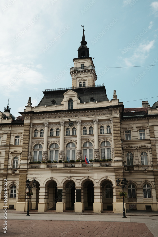 Fototapeta premium Front view of the City Hall of Novi Sad, Serbia, with its elegant neoclassical architecture and national flags.