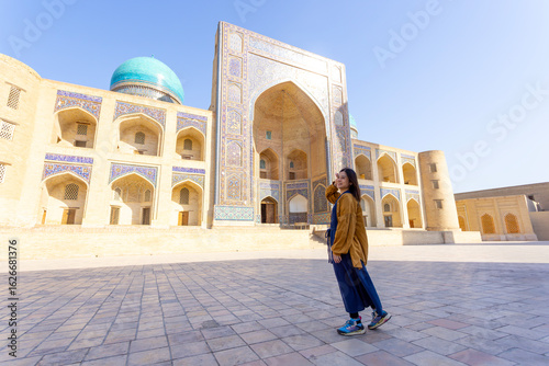woman as a tourist have fun in front of Poi-Kalyan Kalyan mosque in bukhara Uzbekistan	